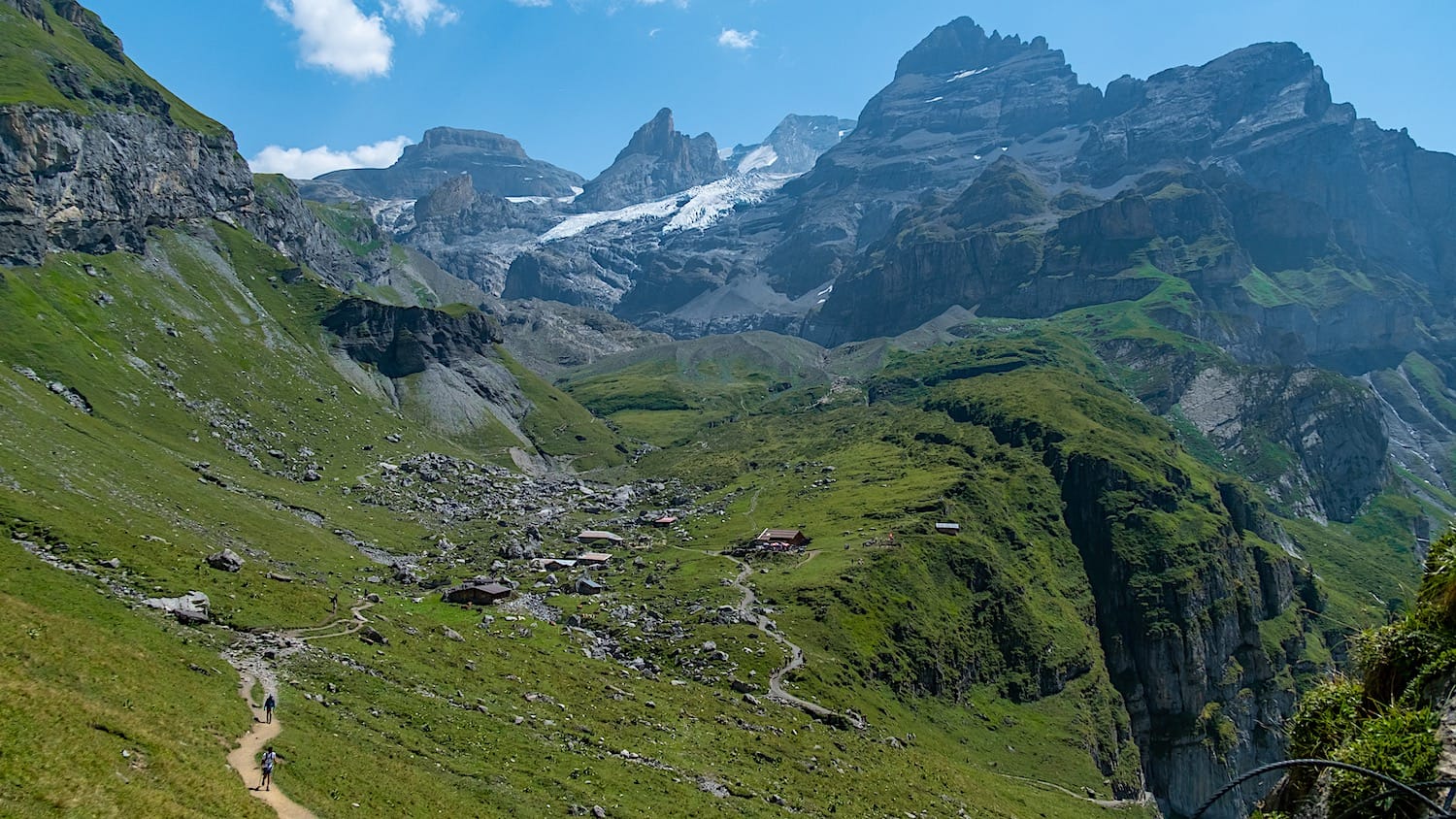 View over the trail and the first hut in the distance from the trail. Some mountains and a glacier on the distance
