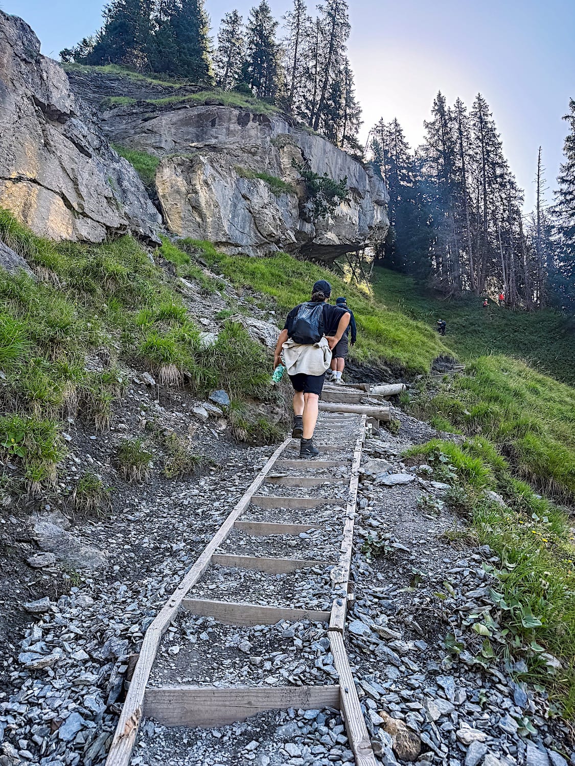 Woman on uphill trail made out of gravel and dirt stairs.