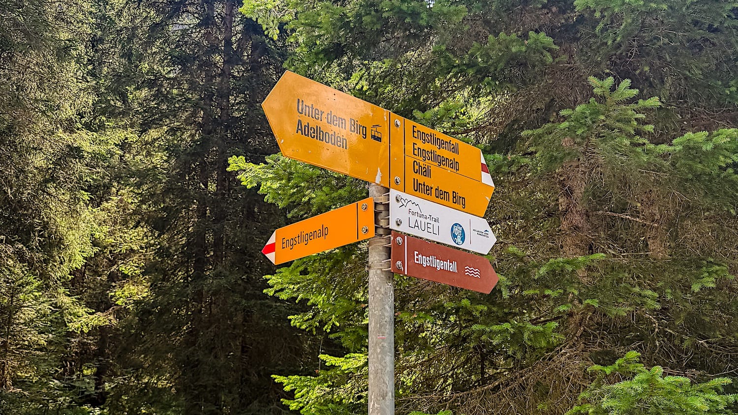Yellow trail signpost pointing to Engstligenfall, Adelboden and Unter dem Birg