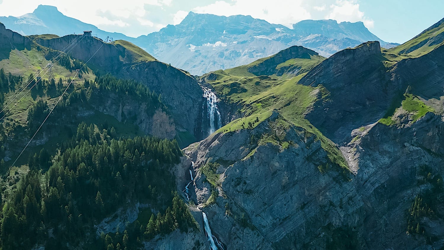 Aerial view of Engstligenfälle cascading down the cliff, with the gondola station visible on the ridge above