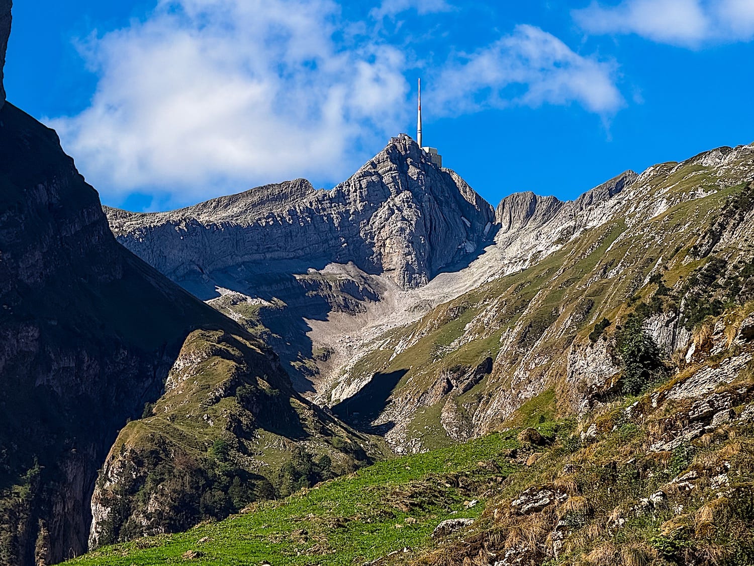 Säntis summit with its antenna seen from the Seealpsee valley, rocky ridges in the foreground