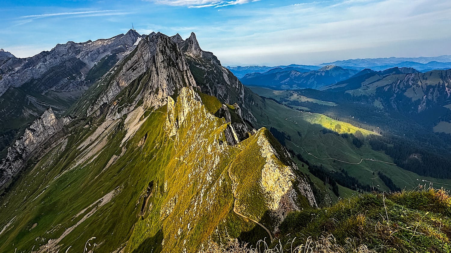 Narrow trail along the grassy Schäfler ridge, jagged peaks and the Appenzell hills beyond