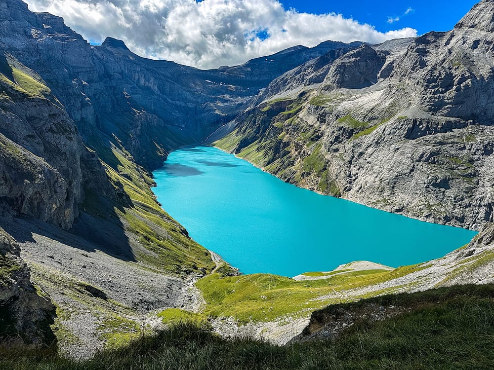 Turquoise Limmernsee reservoir between steep rocky mountain walls under a partly cloudy sky